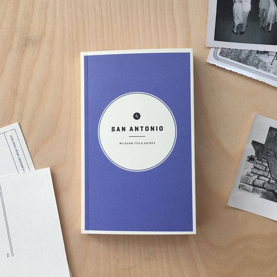 Blue book titled 'San Antonio' on a wooden surface with black and white photos.