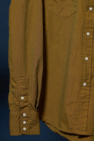 Close-up of a mustard yellow linen shirt with white buttons, showing the chest pocket, button-down front, and a buttoned cuff against a dark blue background.