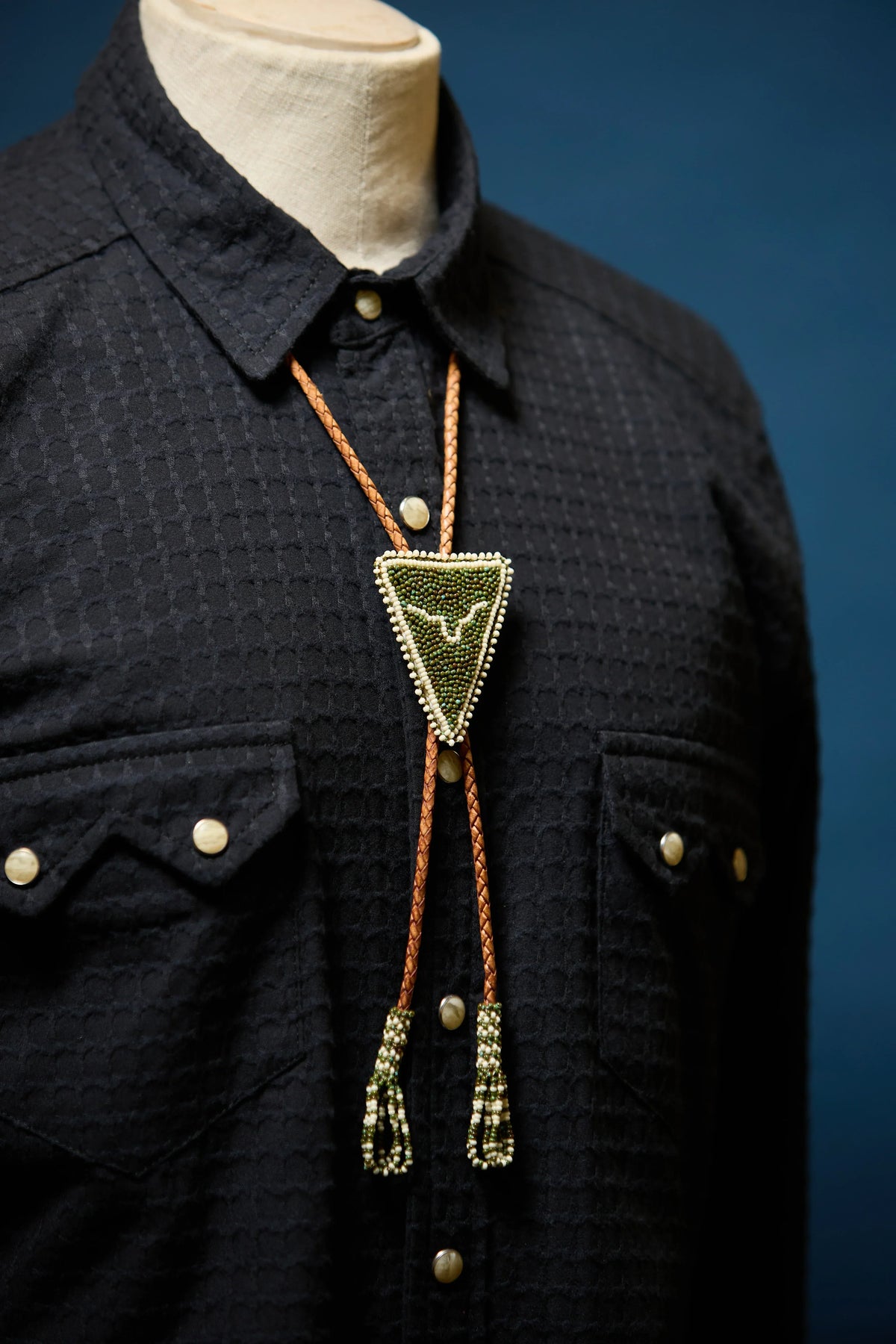 Richter195 front, men's black western pearl snap shirt with beaded bolo tie on mannequin
