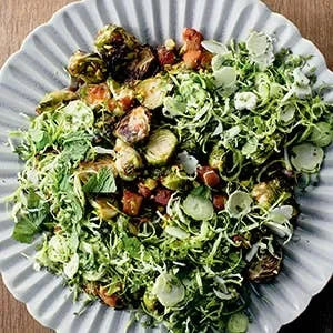 Salad with brussels sprouts, bacon, and croutons on a blue plate