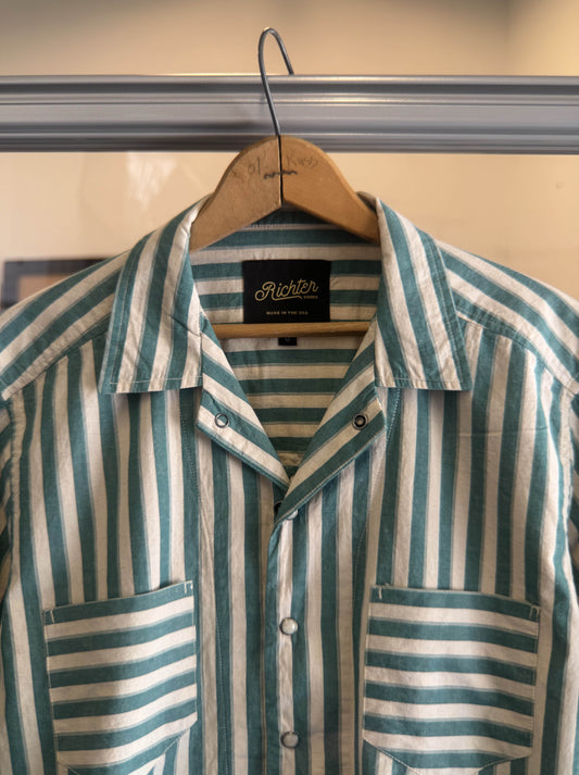 Green and white striped shirt on a hanger From Richter Goods with brand label