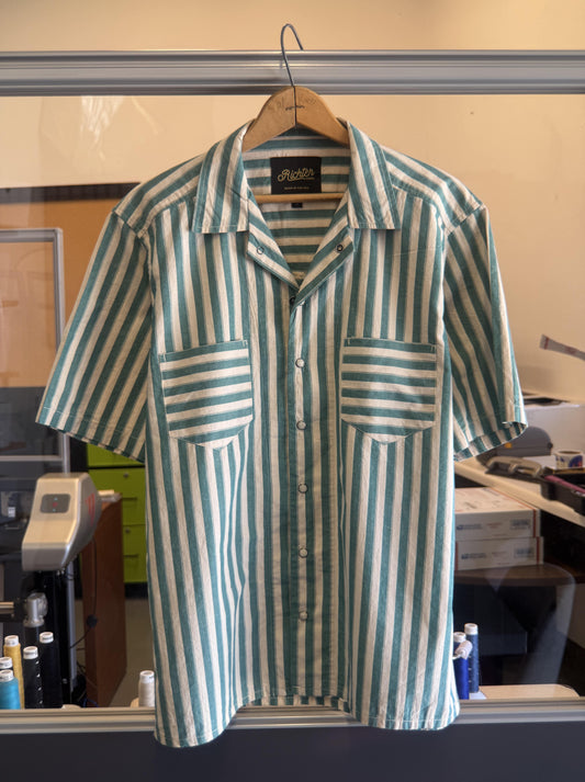 Green and white striped shirt on a hanger in an office setting