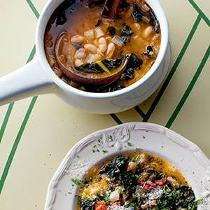 Two bowls of soup with vegetables on a green and white striped tablecloth